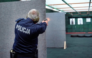 Policjant strzela zza zasłony do tarczy na strzelnicy