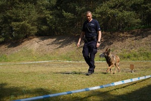 Policjant z psem na placu zawodów.