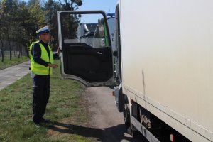 Policjant drogówki kontroluje kierowcę białego samochodu ciężarowego