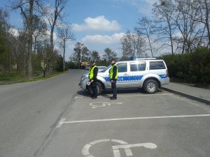 Policjanci ubrani w żółte kamizelki obserwują ruch drogowy