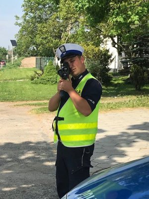 Policjant ruchu drogowego wykonuje pomiar prędkości przy użyciu laserowego miernika