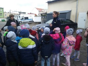 Na dziedzińcu komendy policjantka opowiada o pracy policjantów ruchu drogowego.