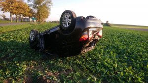 Samochód marki Mitsubishi leżący na dachu na polu