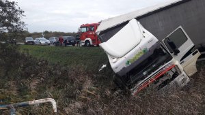 Kabina samochodu ciężarowego wywrócona w przydrożnym rowie. Z lewej strony widać zaparkowane pojazdy służb ratunkowych.