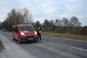 Policjant kontroluje trzeźwość kierowcy jadącego czerwonym samochodem dostawczym.