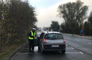 Policjant ruchu drogowego stoi w pobliżu samochodu, który kontroluje.