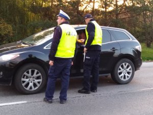 Policjant OPI oraz ruchu drogowego podczas kontroli samochodu osobowego.