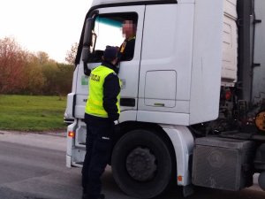 Policjant wykonuje sprawdzenie stanu trzeźwości kierowcy ciągnika siodłowego.