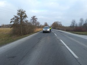 Policjant ruchu drogowego kontroluje kierowcę samochodu osobowego.