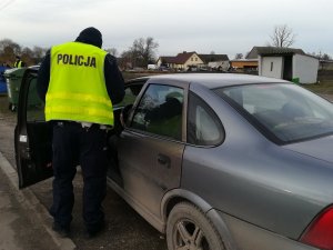 Policjant ruchu drogowego kontroluje dokumenty, które okazał kierujący.