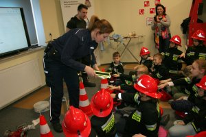 Policjantka wręcza dzieciom odblaskowe opaski.