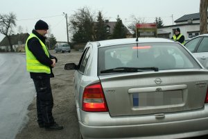 Po lewej stronie policjant ruchu drogowego, z prawej strony pojazd marki Opel, którego kierująca jest kontrolowana.