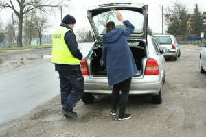 Policjant ruchu drogowego kontroluje przewożony bagaż oraz obowiązkowe wyposażenie samochodu.