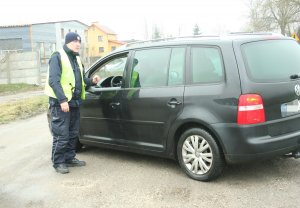 Funkcjonariusz podczas legitymowania kierowcy, który znajduje się w pojeździe.