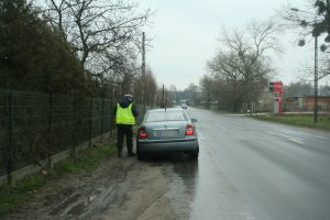 Policjant ogniwa ruchu drogowego podczas kontroli osobowej skody.