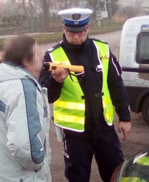 Policjant ruchu drogowego sprawdza trzeźwość kierującego przy użyciu alkomatu.