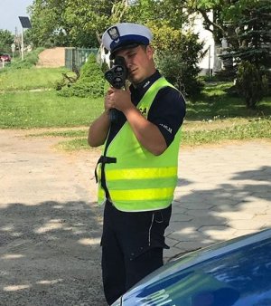 Policjant ruchu drogowego wykonuje pomiar prędkości przy użyciu laserowego miernika