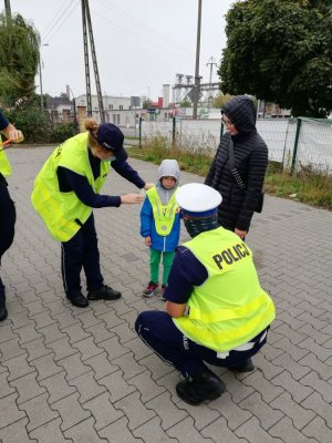 policjantka zakłada chłopcu element odblaskowy