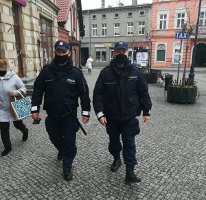 Dwóch policjantów idących przez miasto chodnikiem