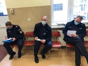 zdjęcie przedstawia trzech policjantów wypełniających ankietę do szczepień przeciwko covid-19