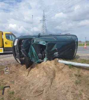 Na zdjęciu widoczny jest samochód lezący w rowie, i uszkodzony słup oświetleniowy