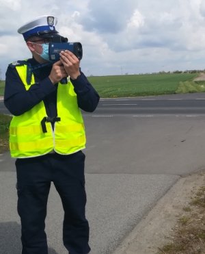 Na obrazku widoczny jest policjant który mierzy prędkość pojazdów