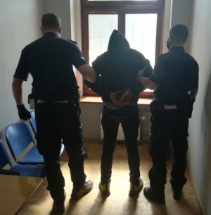 Na zdjęciu jest dwóch policjantów, którzy stoją z zatrzymanym