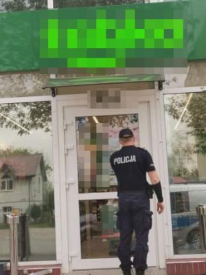 policjant wchodzący do sklepu w celu kontroli obostrzeń