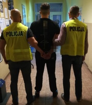 na obrazku widoczni są policjanci wraz z osoba zatrzymaną