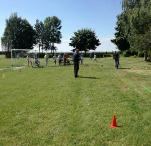 Na zdjęciu widoczny jest policjant i uczniowie którzy przygotowują się do  egzaminu na kartę rowerową