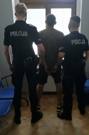 Na zdjęciu widoczni są  umundurowani policjanci wraz z zatrzymanym