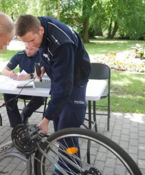 Na obrazku znajduje się policjant który znakuje rower