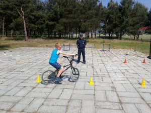 obrazek przedstawia policjanta umundurowanego i chłopca pokonującego tor przeszkód na kartę rowerową