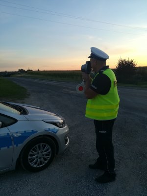 obrazek przedstawia policjanta, który mierzy prędkość pojazdu