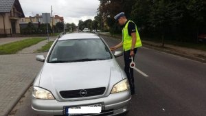 na obrazku widoczny jest policjant, który sprawdza stan trzeźwości kierującego pojazdem