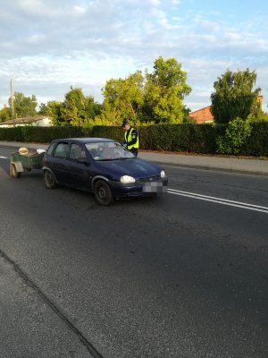 na obrazku widoczny jest policjant, który kontroluje stan trzeźwości kierowcy samochodu osobowego