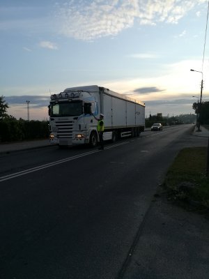 obrazek przedstawia policjanta, który kontroluje stan trzeźwości kierowcy pojazdu ciężarowego