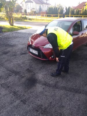 na obrazku widoczny jest policjant, który sprawdza oświetlenie w pojeździe