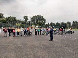 na obrazku widać policjanta oraz dzieci na rowerach , które przygotowują się do egzaminy na kartę rowerową