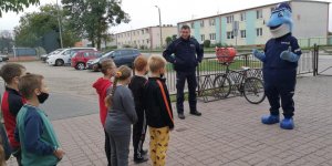 na zdjęciu widoczny jest policjant z grupą dzieci oraz policjant przebrany za pluszaka