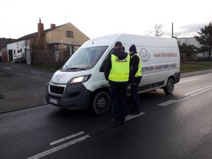 Działania trzeźwy kierujący. Policjanci sprawdzają stan trzeźwości kierowcy białego samochodu dostawczego.