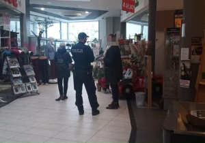 umundurowany policjant  rozmawia z kobietą na  holu galerii handlowej