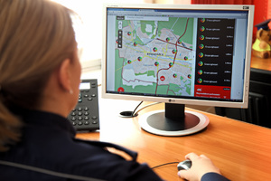 Policjantka siedzi przed monitorem komputerowym, na którym jest wyświetlona krajowa mapa zagrożeń bezpieczeństwa