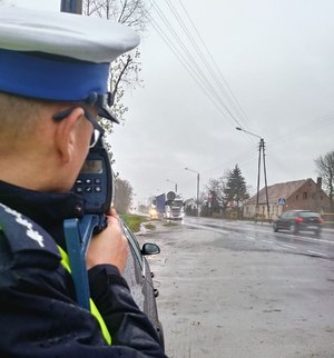 Policjant wykonuje pomiar prędkości przy użyciu laserowego miernika