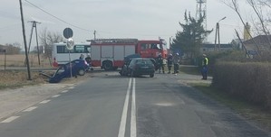 Droga, na którego zjadają się rozbite  pojazdy, wóz strażacki.  Na pasie ruchu stoją policjanci oraz strażacy