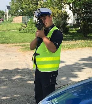 Policjant wykonuje pomiar prędkości przy użyciu laserowego miernika.