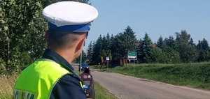 Policjant ruchu drogowego przy użyciu laserowego miernika sprawdza prędkość nienajeżdżających pojazdów