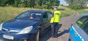 Policjant podczas kontroli samochodu osobowego koloru niebieskiego