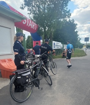 Dzielnicowi z rowerami stoją przy bramie startowej.