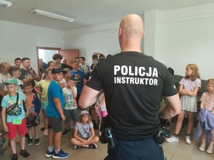 Sala odpraw w KPP. Instruktor taktyk i technik interwencji pokazuje środki przymusu bezpośredniego.